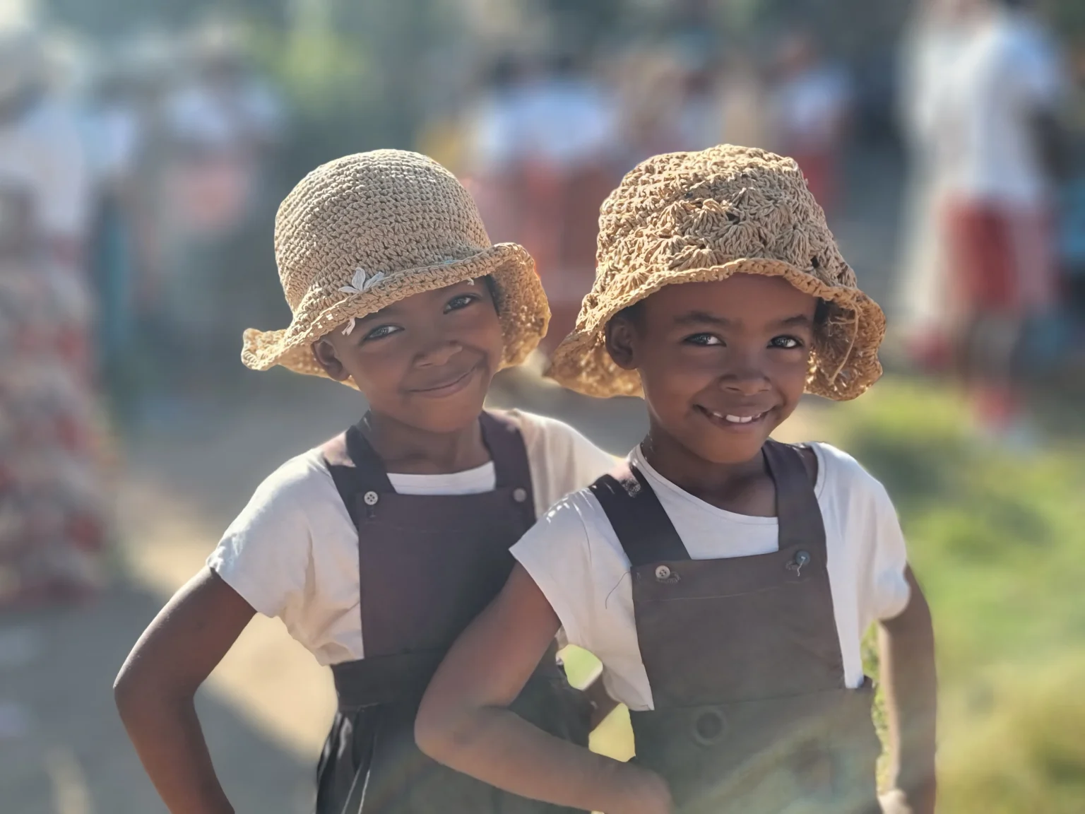 Twin sisters in straw hats smiling in Mananjary